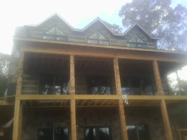 Dormers and porch framing on a large log home under construction — Roof Coating work by our crew in Douglas