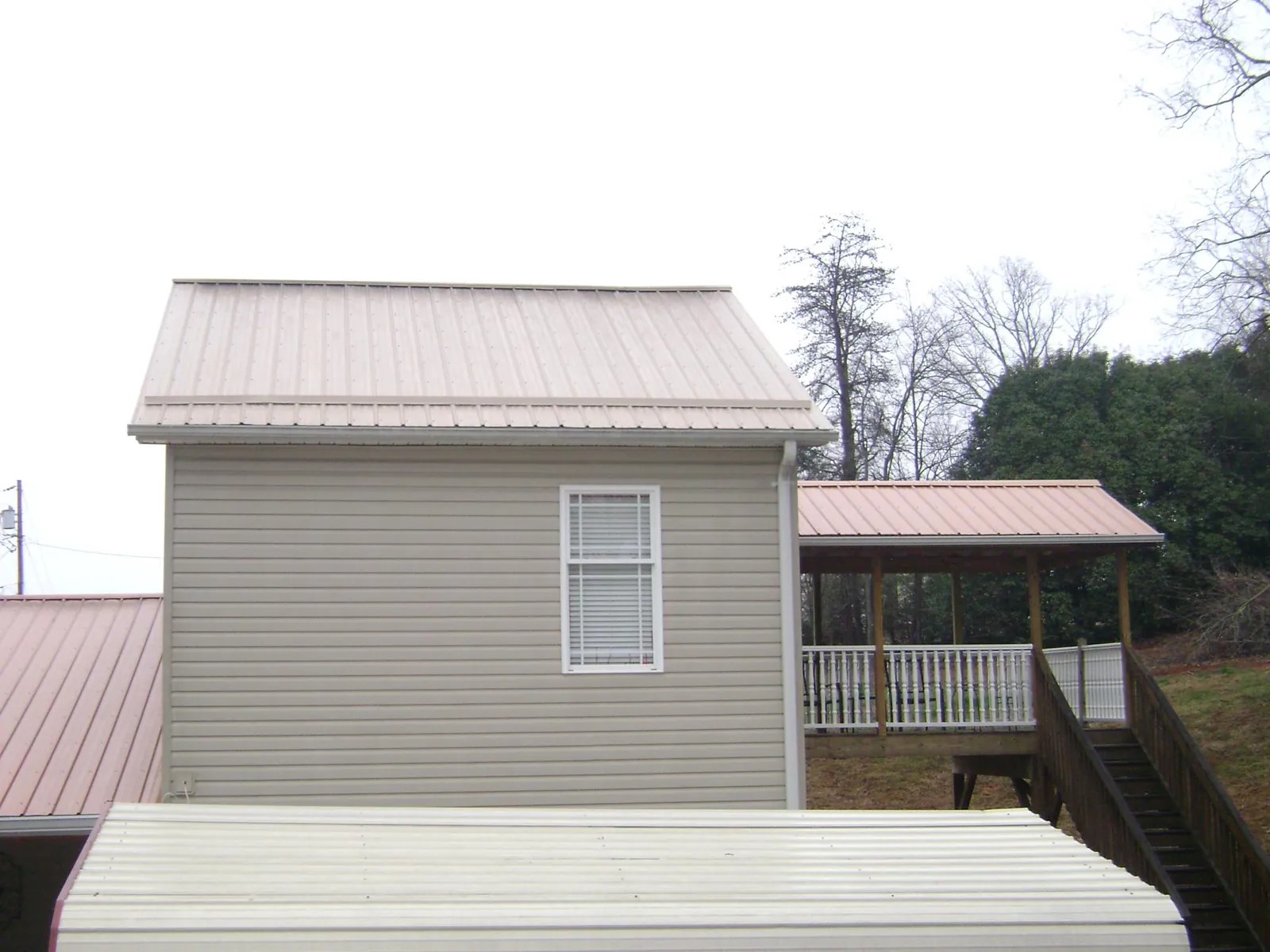 Tan metal roofs on a two story addition and attached porch, from a Roof Replacement job in Douglas